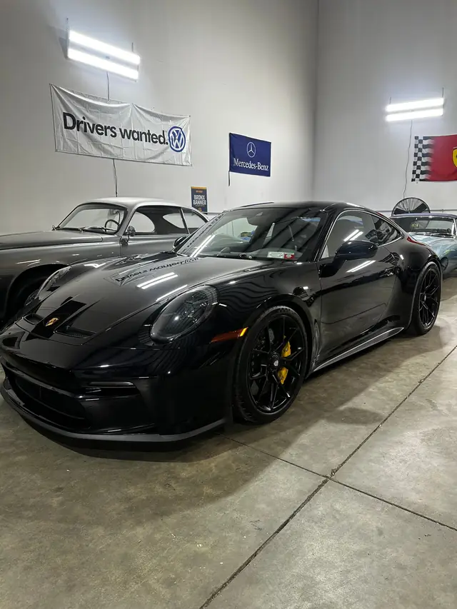 Black Porsche 911 with yellow brake calipers parked in the bay