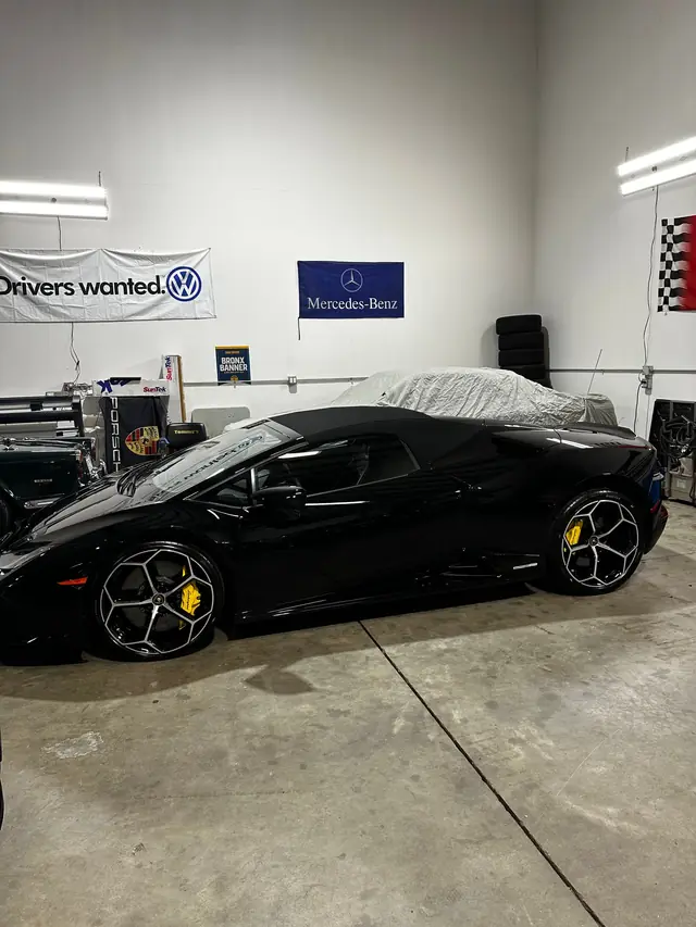 Black Lamborghini under a partial cover in the shop