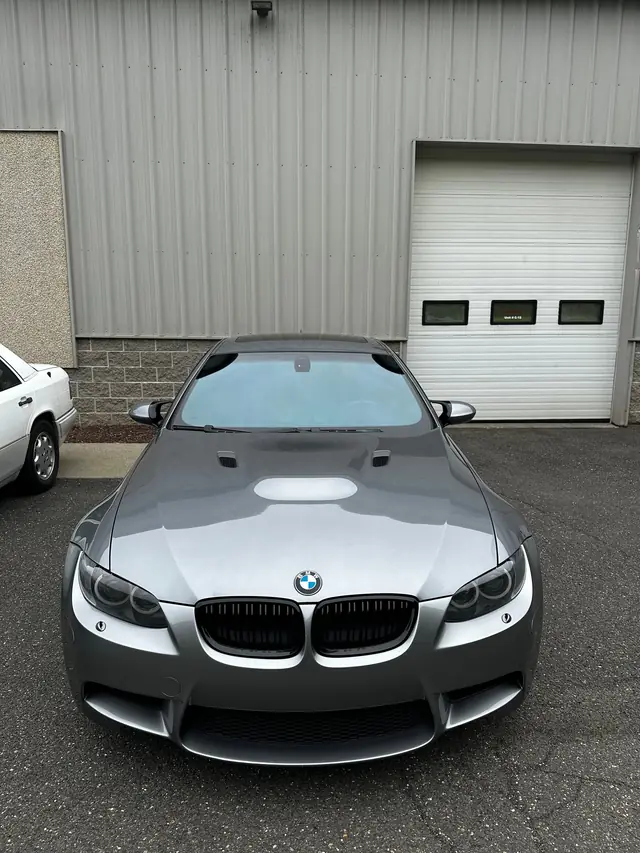 Grey BMW M3 facing the camera outside the shop door