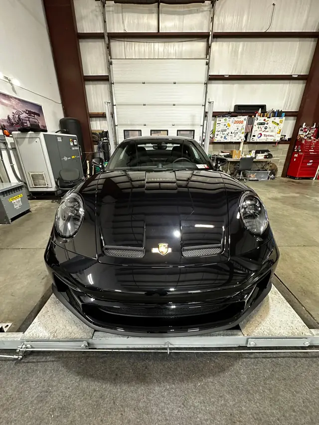 Black Porsche 911 up on the lift, seen from the front