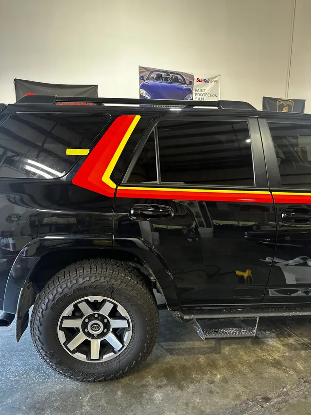 Black Toyota 4Runner with a red and yellow side stripe, close on the wheel