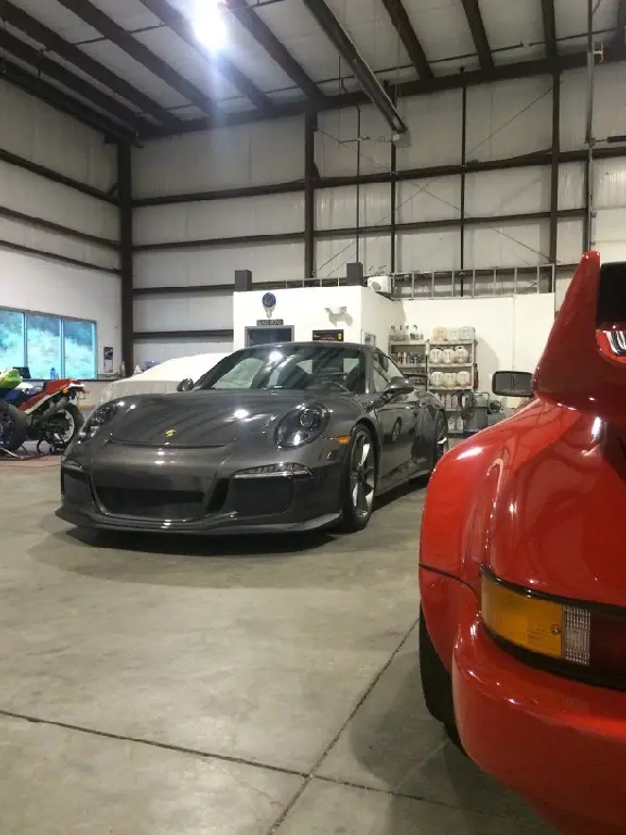 Porsche GT3 beside a red 911 in the shop